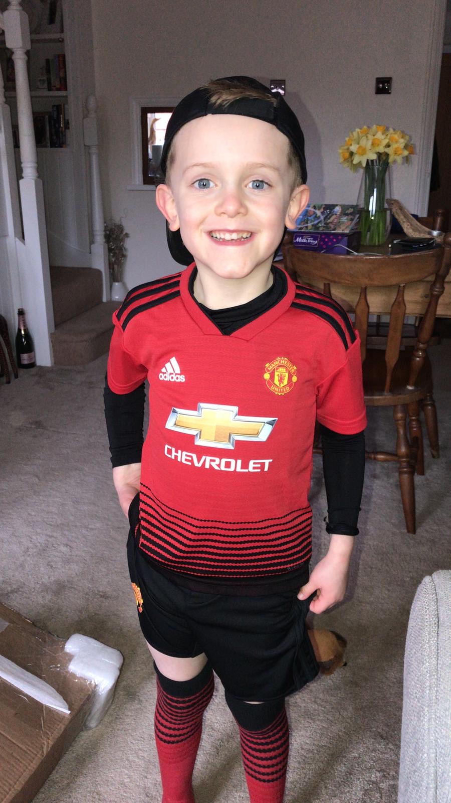 Dylan in his football kit, grinning on the pitch